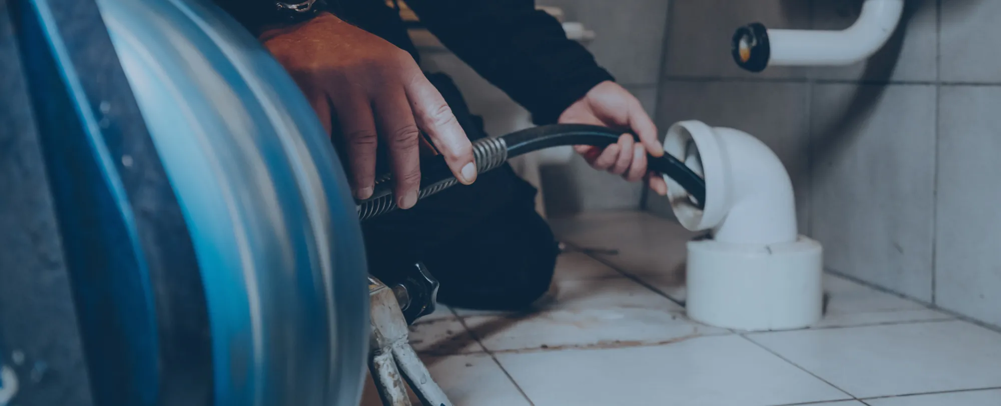 Mann mit Schlauch im Abfluss