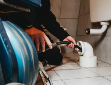 Mann mit Schlauch im Abfluss